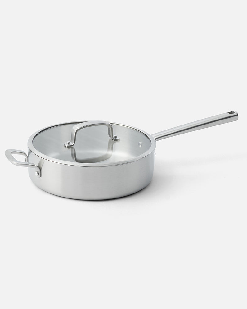 Stainless steel sauté pan with lid and long handle on a white background