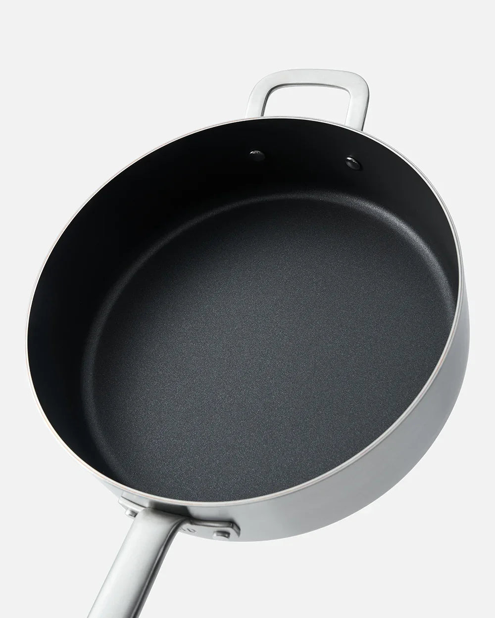 Top view of a silver Mako saute pan with non-stick black interior and two handles on white background