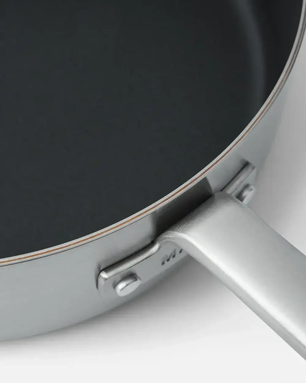 Close-up of a stainless steel nonstick sauté pan with a sturdy handle on white background