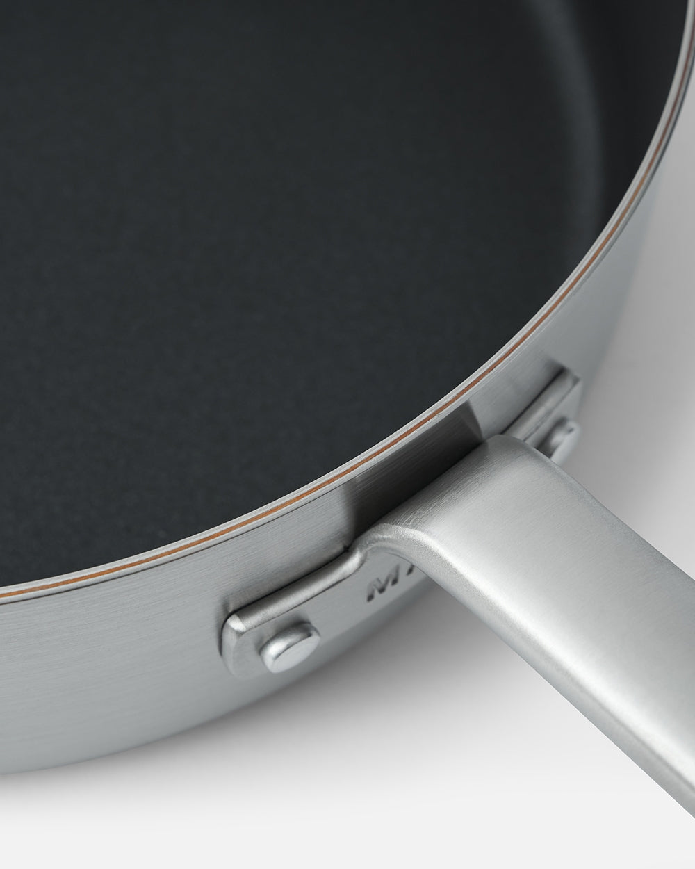 Close-up of a stainless steel nonstick sauté pan with a sturdy handle on white background