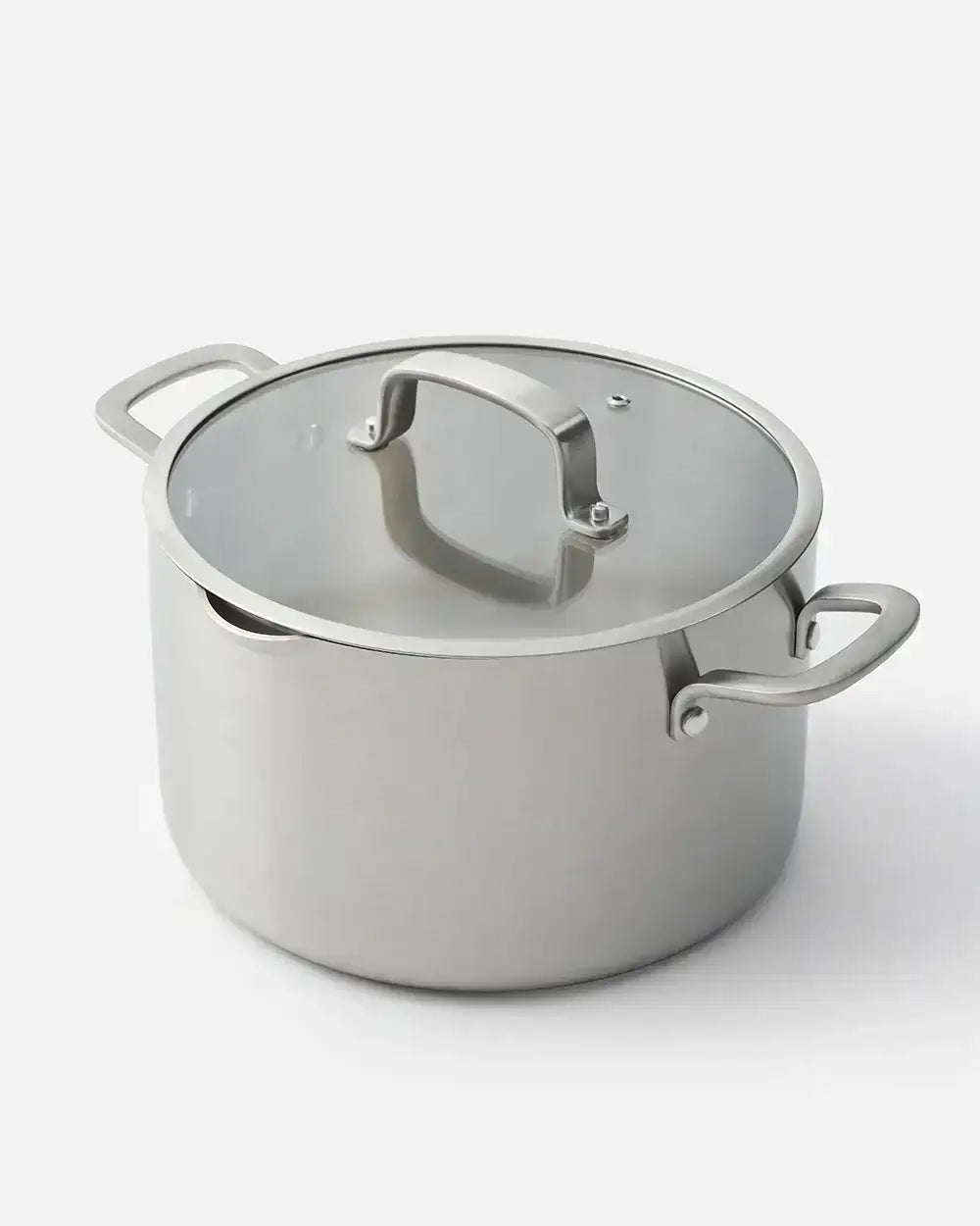 Stainless steel stockpot with glass lid and side handles on a white background