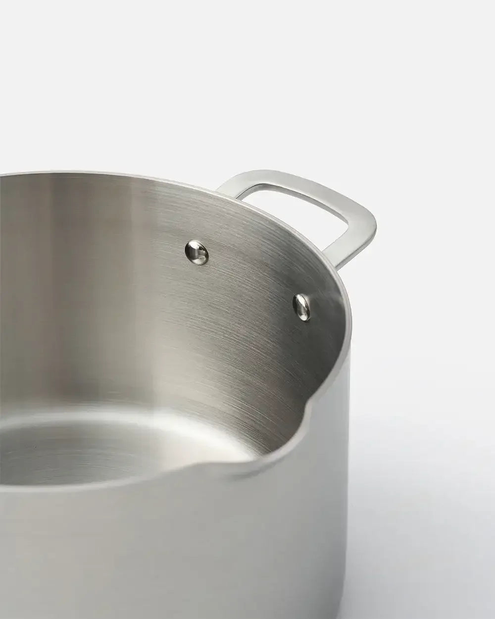 Stainless steel stockpot with riveted handle and brushed finish on white background