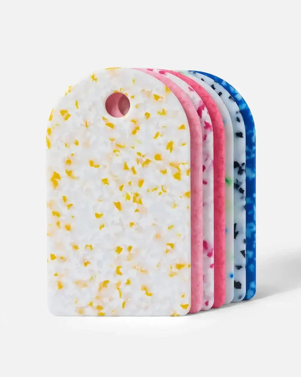 Stack of colorful terrazzo-patterned cutting boards with rounded tops on white background