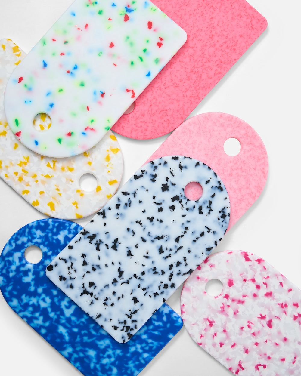 Set of colorful terrazzo-patterned resin kitchen boards in various colors on white background