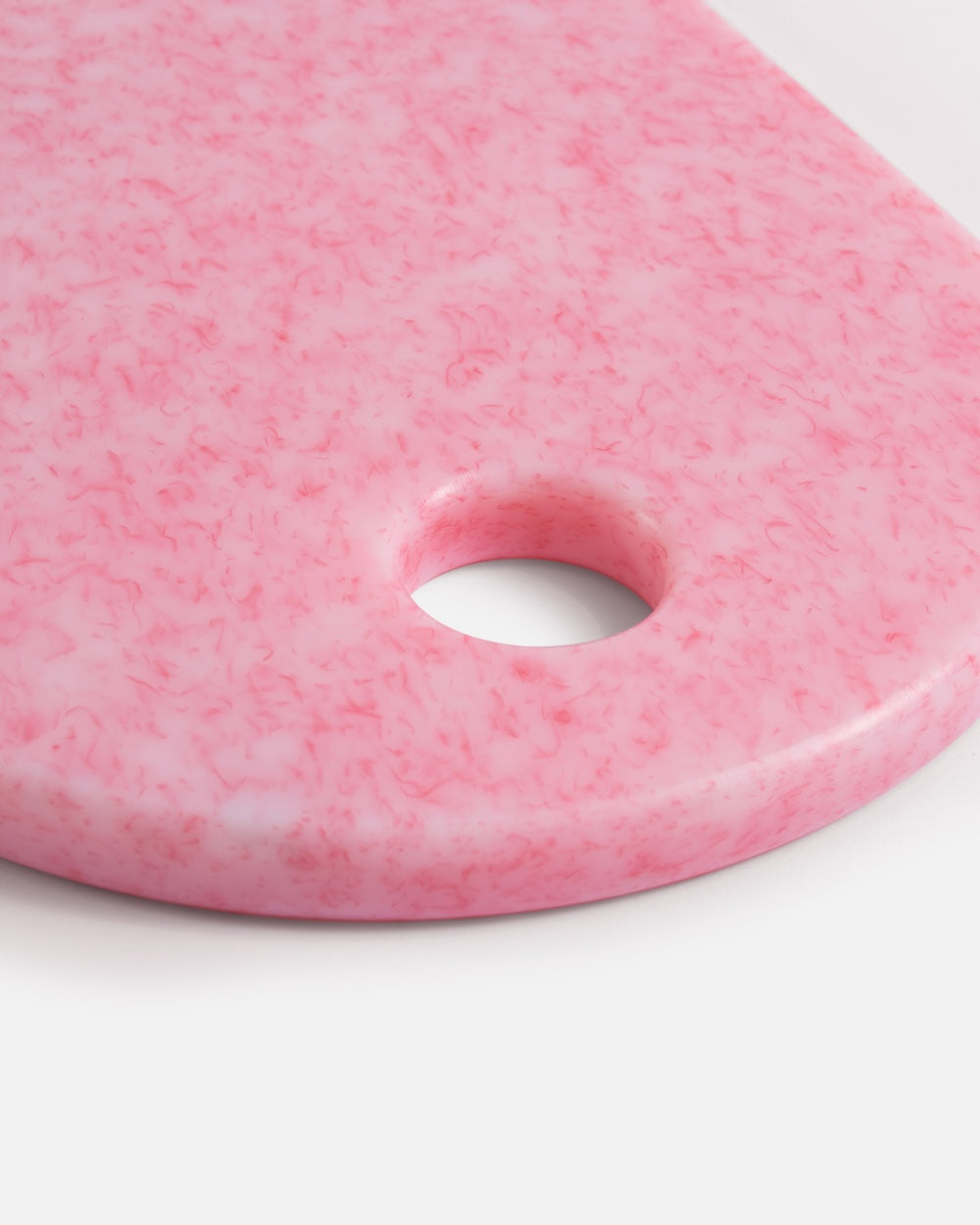 Close-up of pink speckled chopping board with rounded edge and hanging hole