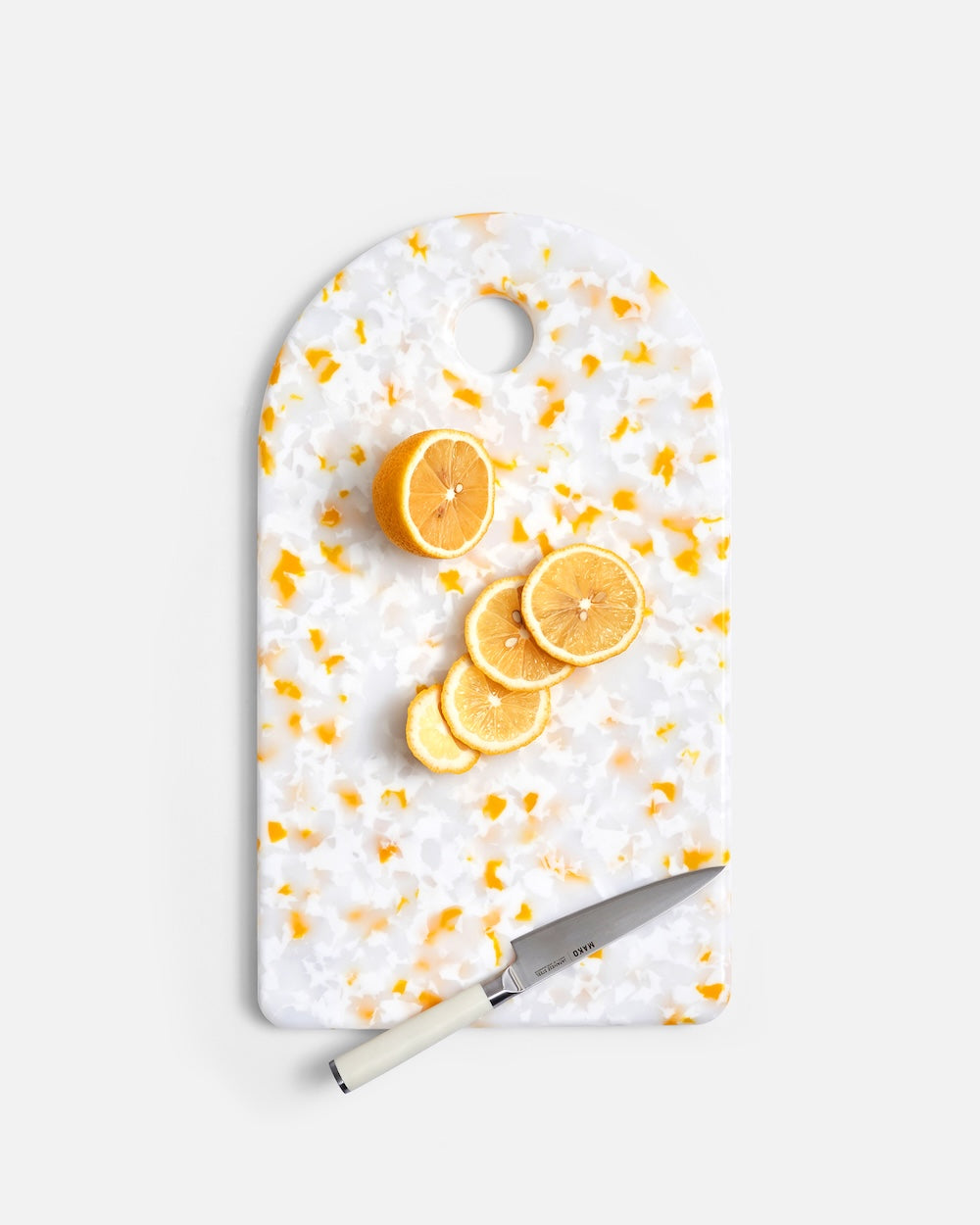 Lemon slices and knife on terrazzo cutting board with yellow and white pattern
