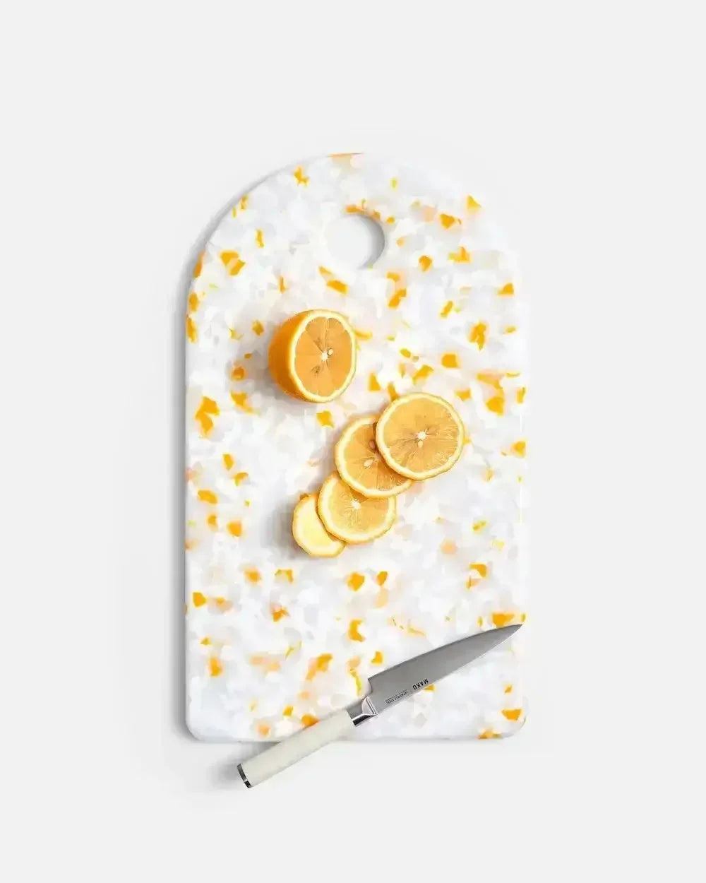 Sliced lemon and kitchen knife on terrazzo cutting board with yellow accents
