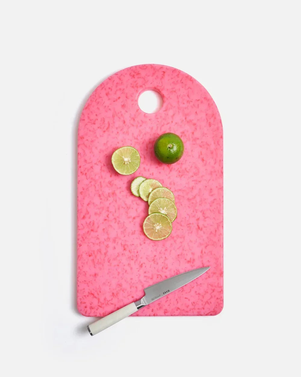Pink Mako cutting board by Marion Grasby with sliced green lime and white-handled kitchen knife