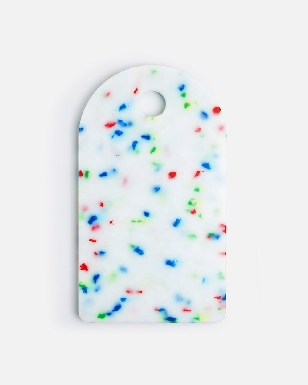 White cutting board with colorful red, blue, and green speckles on a plain background