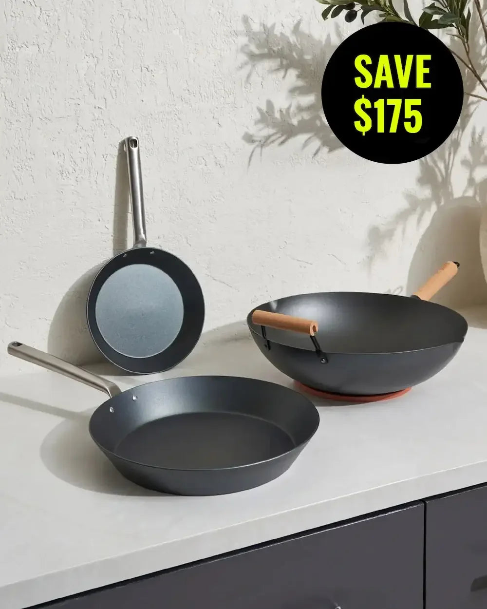 Set of nonstick wok and fry pans with steel and wood handles on kitchen counter, save $175