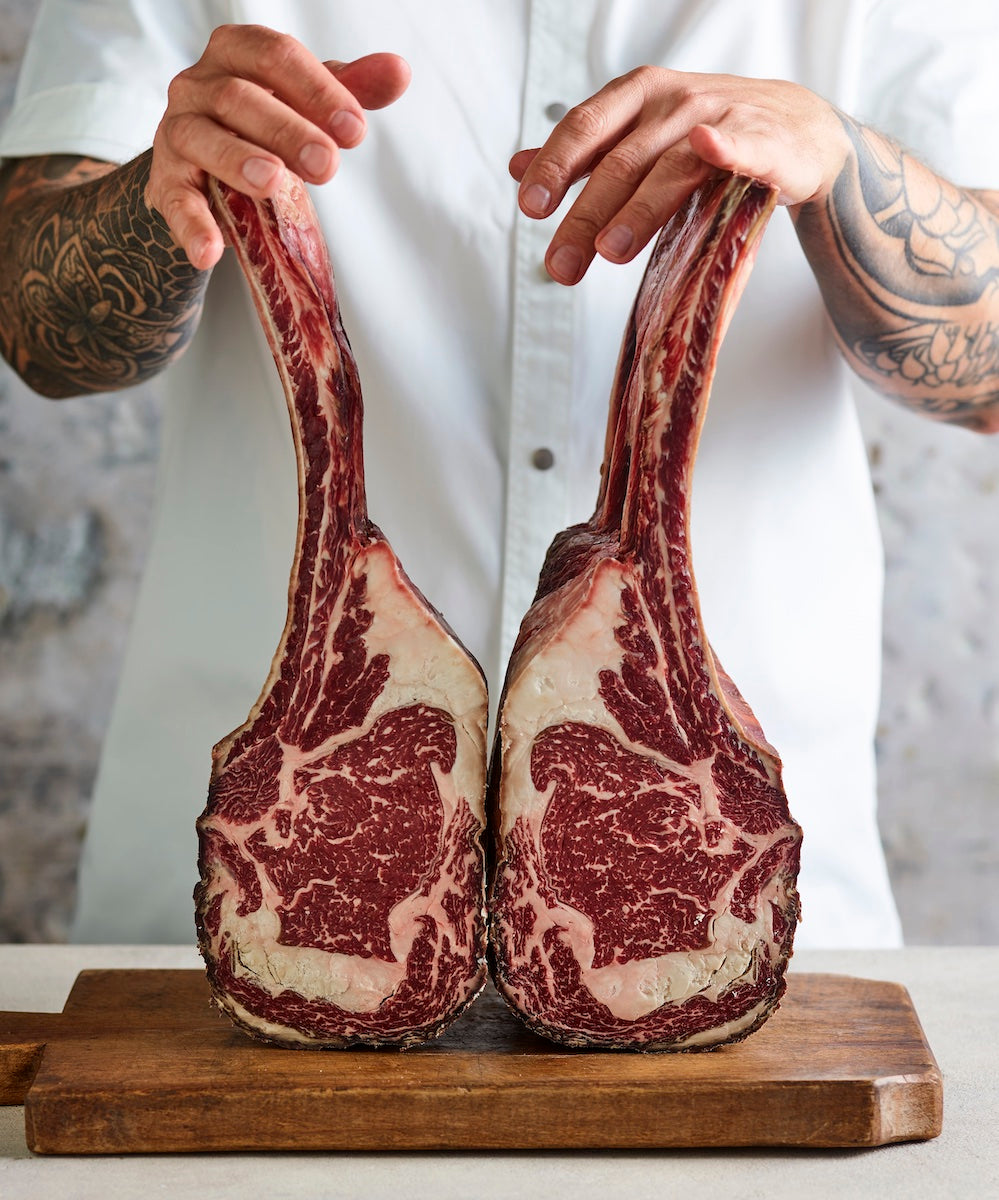 Chef holding a large raw tomahawk steak