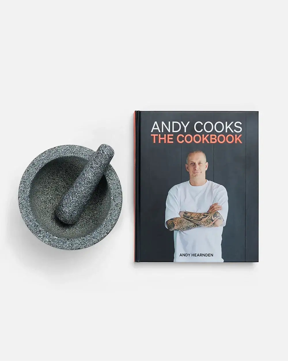Grey granite mortar and pestle next to Andy Cooks cookbook by chef Andy Hearnden