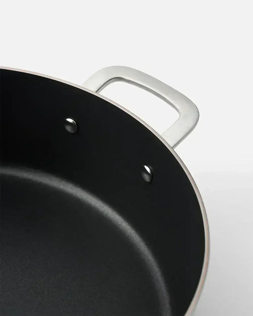 Close-up of nonstick black saucepan with metal handle on light background