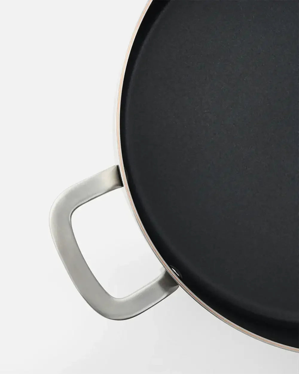 Close-up of a black nonstick essential pan with stainless steel handle on white background