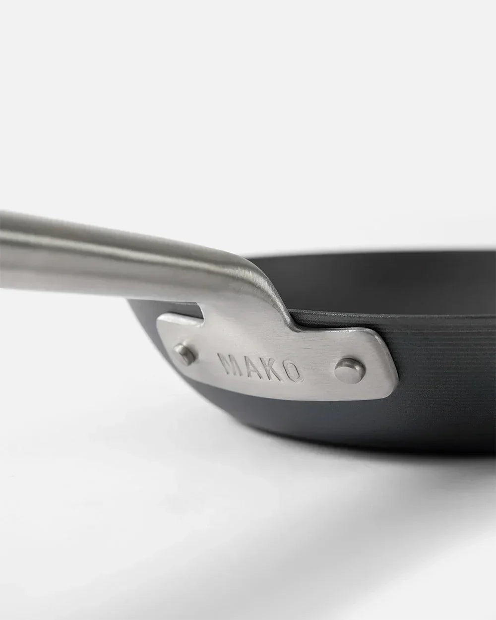 Close-up of black MAKO frying pan with stainless steel handle on white background