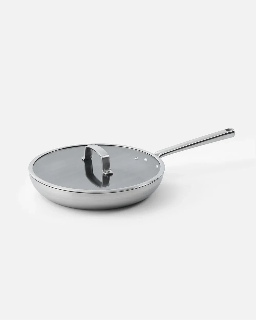 Stainless steel frying pan with glass lid and long handle on white background