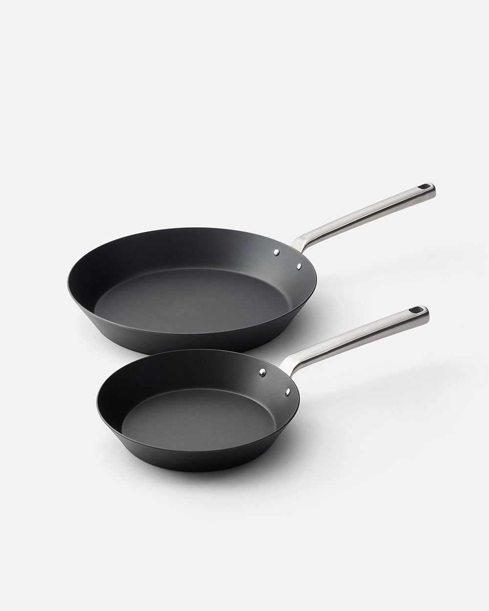 Two black nonstick frying pans with metal handles on a white background