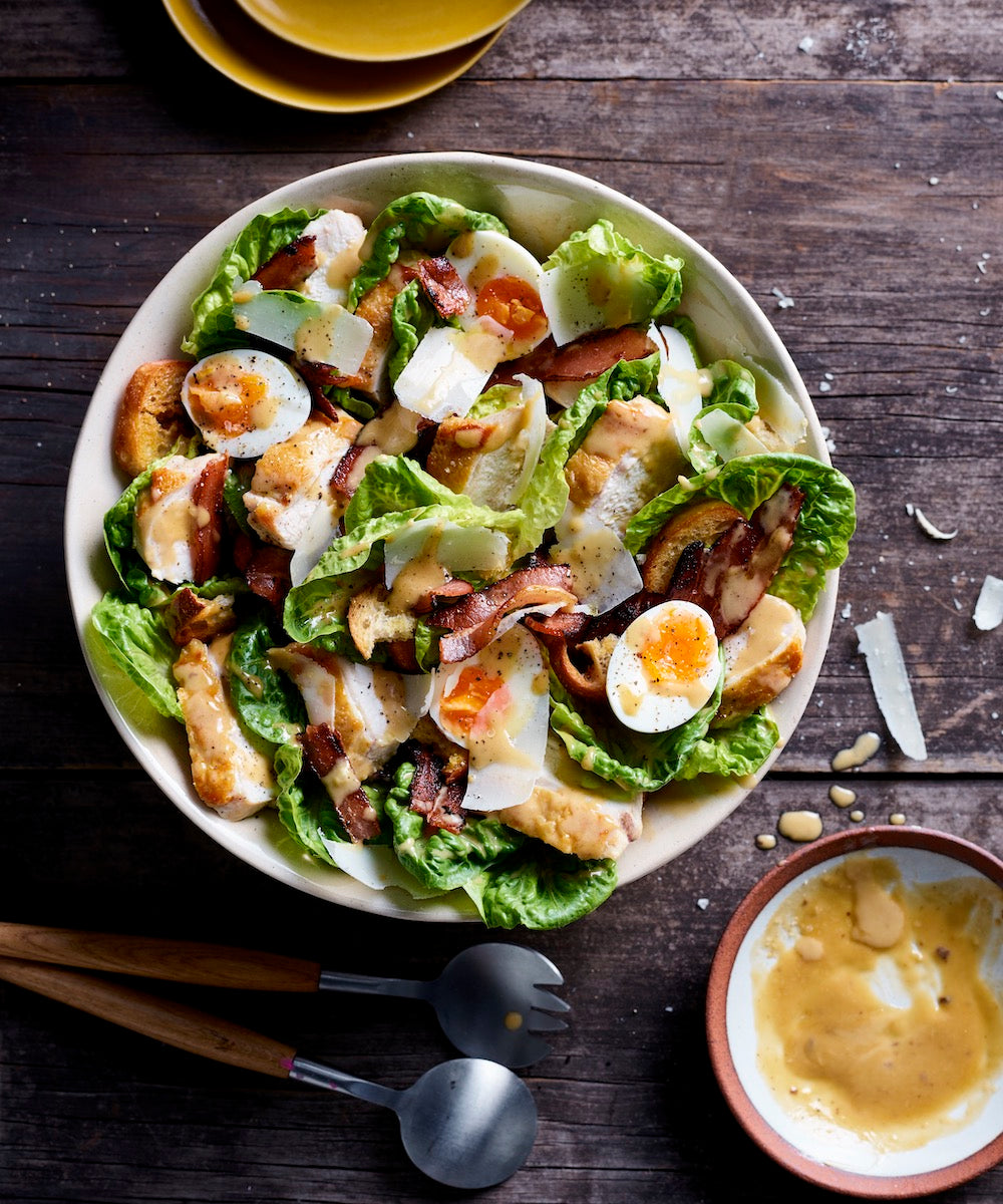 Caesar salad with bacon, croutons and soft-boiled egg in a bowl