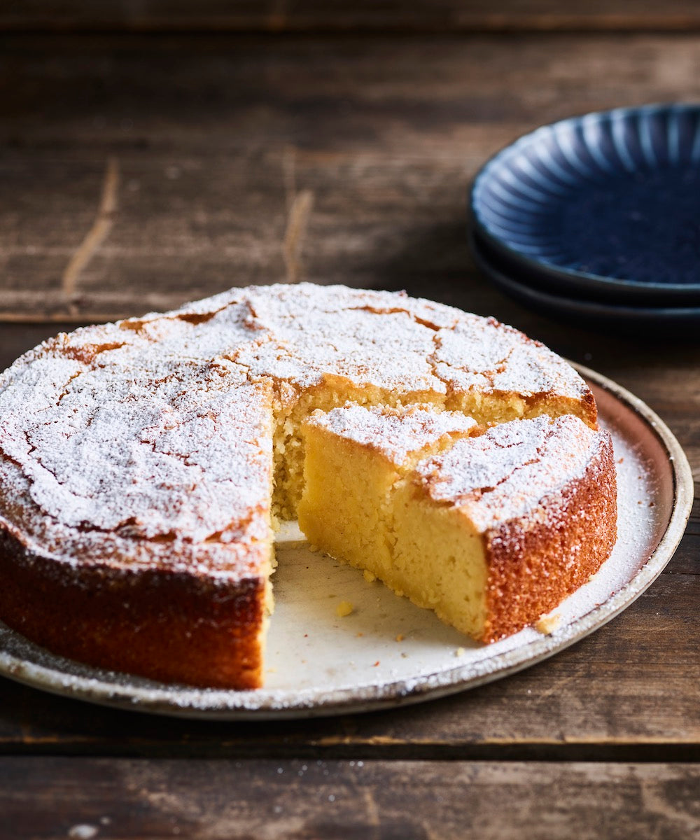 Lemon olive oil cake dusted with icing sugar, one slice removed