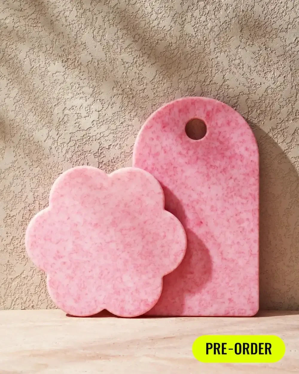 Pink marble cutting boards, one flower-shaped and one rectangular, on textured surface