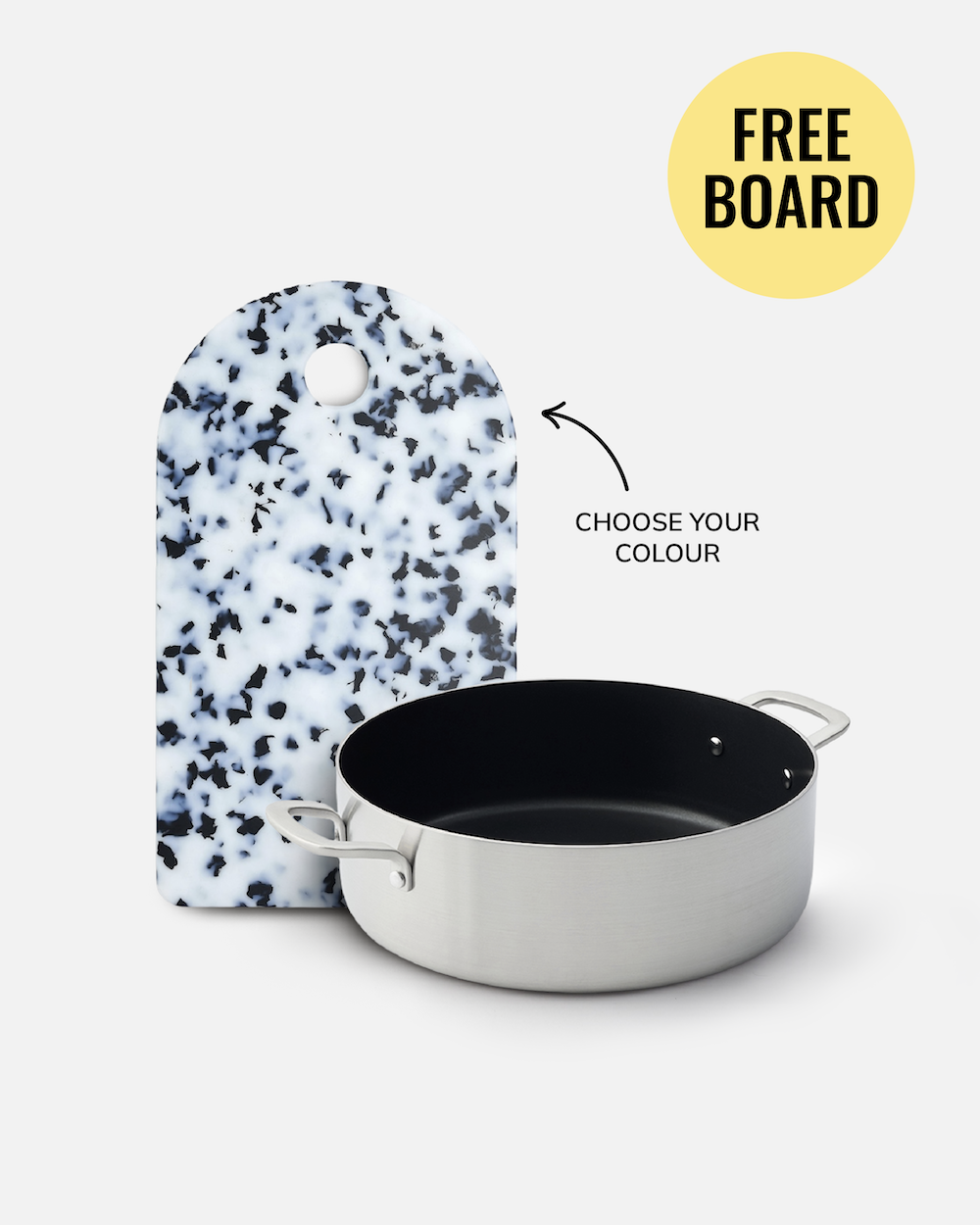A stainless steel saucepan with a black interior sits in front of a white cutting board with black speckles. Text on the image reads 'CHOOSE YOUR COLOUR' with an arrow pointing to the cutting board, and a yellow circle says 'FREE BOARD'.