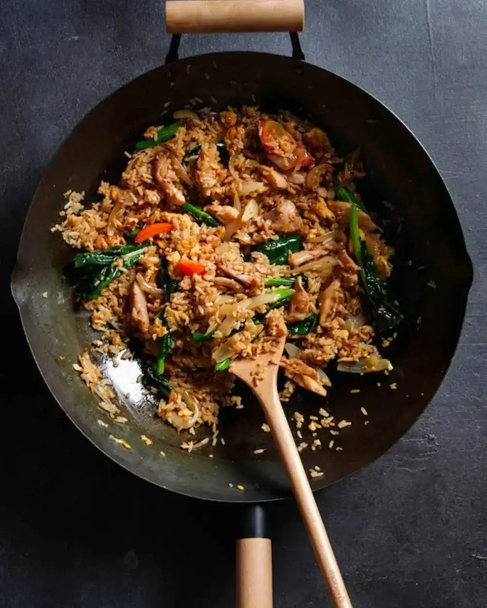 Thai chicken fried rice in a Mako wok with vegetables and wooden spatula, CookDineHost