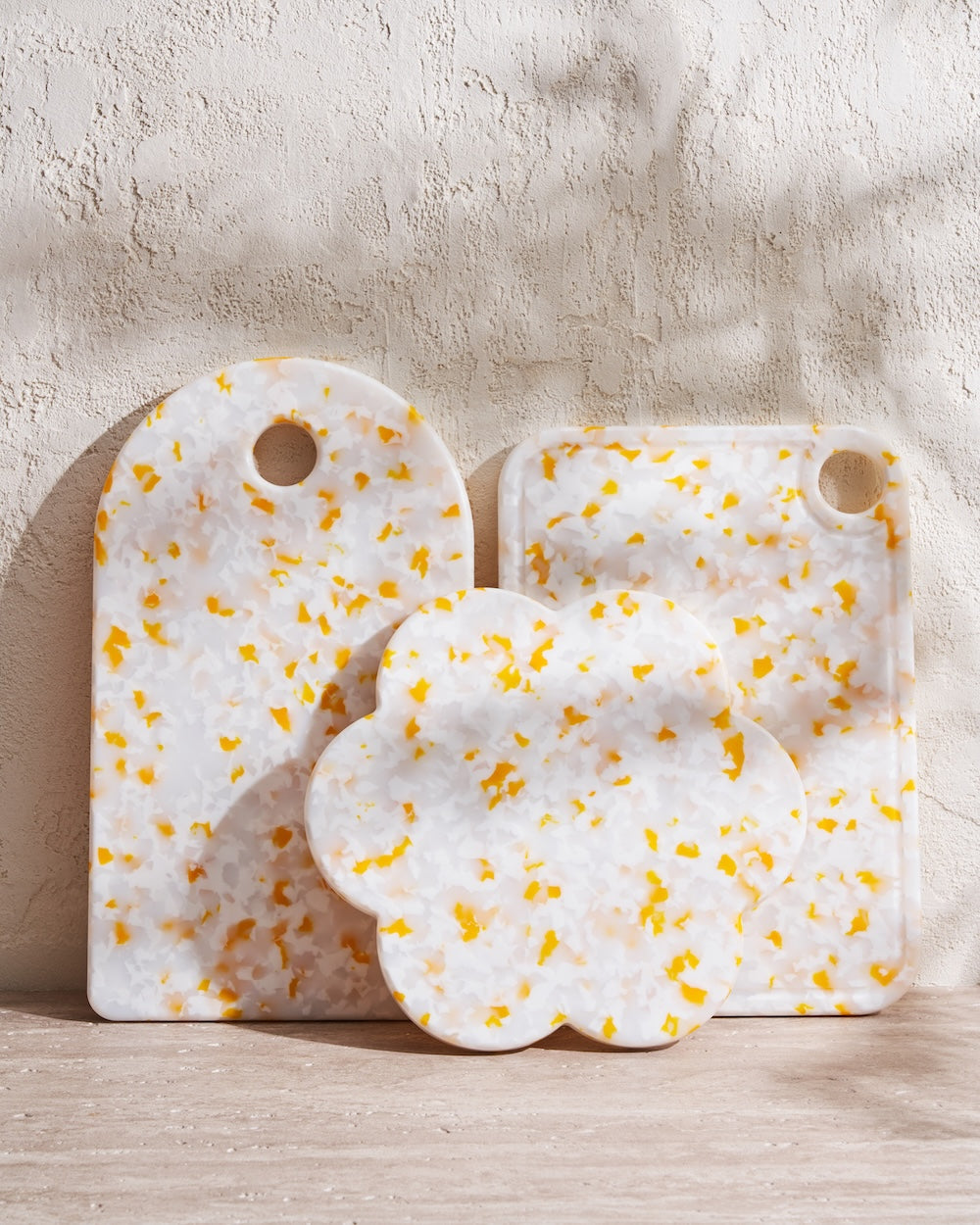 Set of three recycled chopping boards in white with yellow speckles on a textured surface