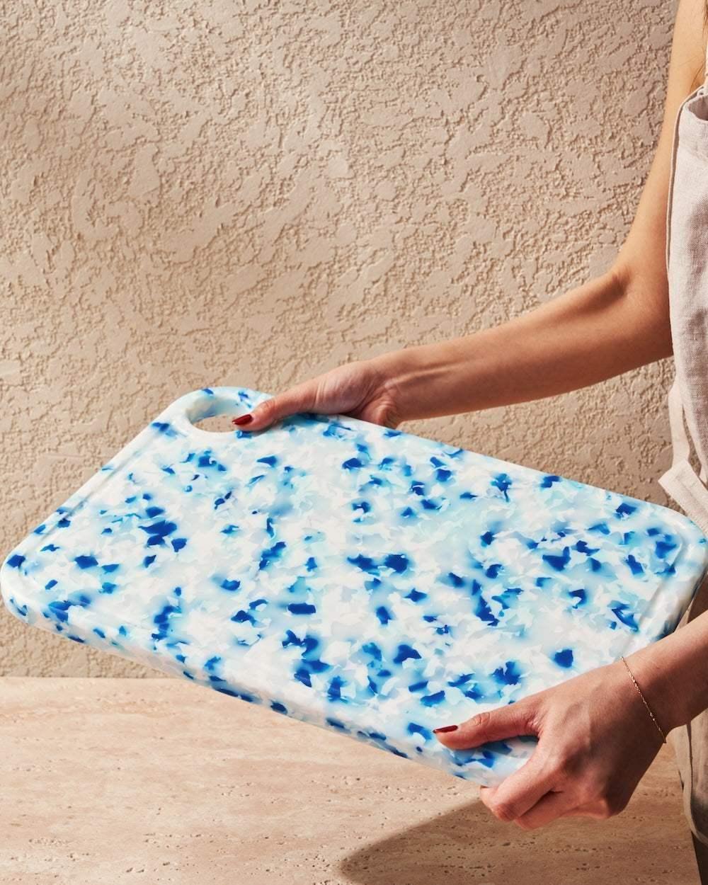 Person holding blue and white recycled chopping board with terrazzo pattern