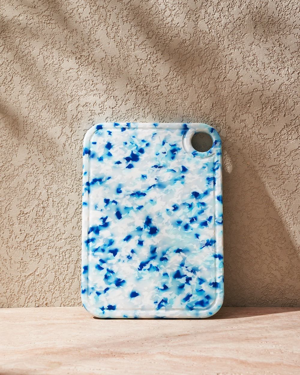 Rectangular blue and white recycled chopping board with rounded edges and a hanging hole