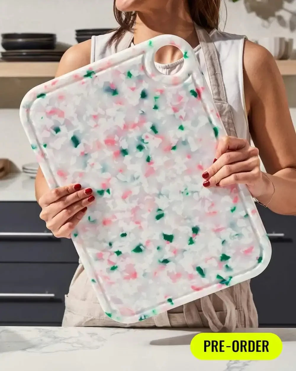 Person holding a large recycled chopping board with pink and green speckled pattern in kitchen