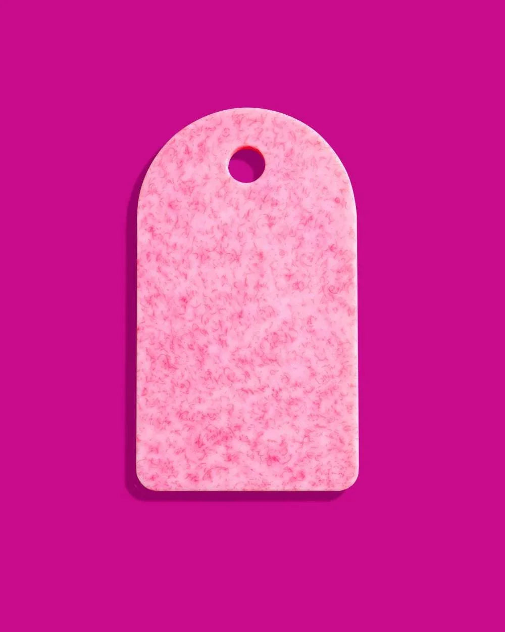 Pink recycled Asoke chopping board with marbled texture and hole on magenta background, Marion Grasby