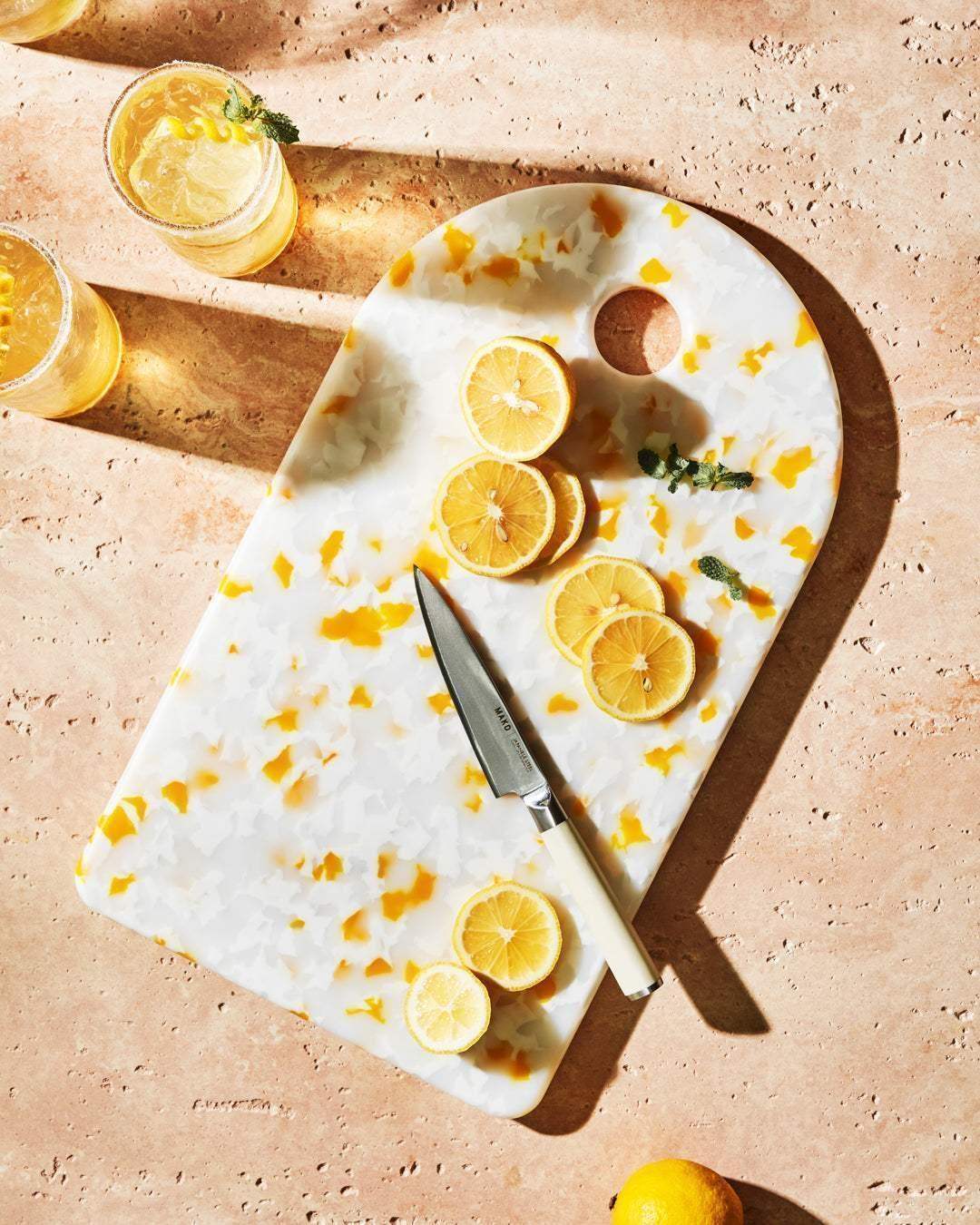 Asoke chopping board by Marion Grasby with sliced lemons and Mako knife on textured surface