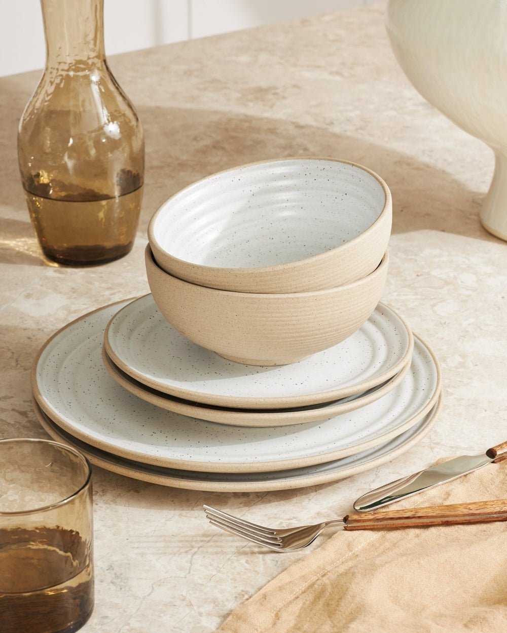 Modern stoneware dinnerware set with plates and bowls on a beige tabletop