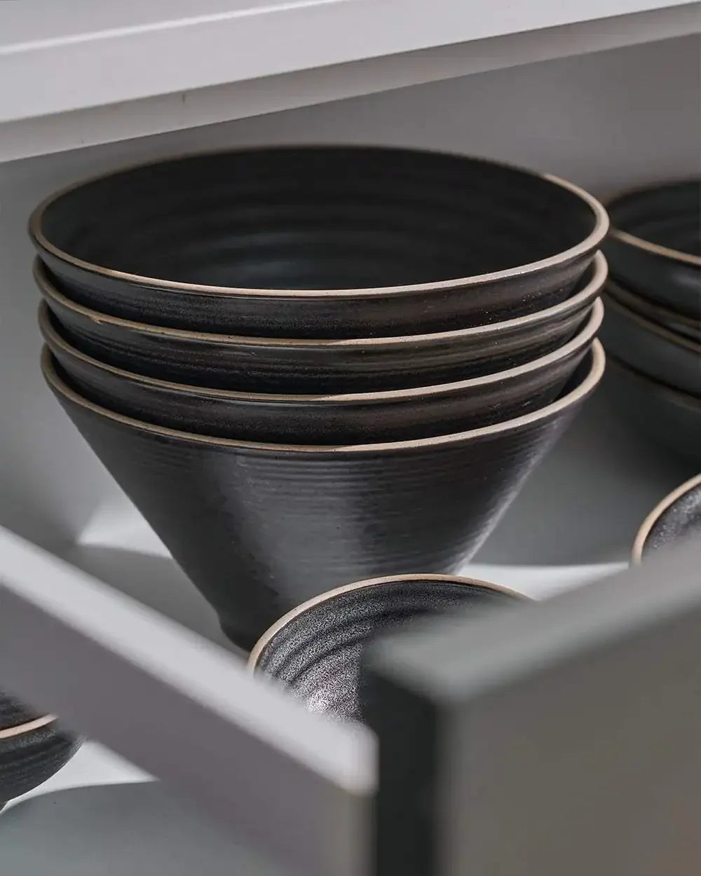 Set of four charcoal ceramic noodle bowls stacked in a kitchen drawer