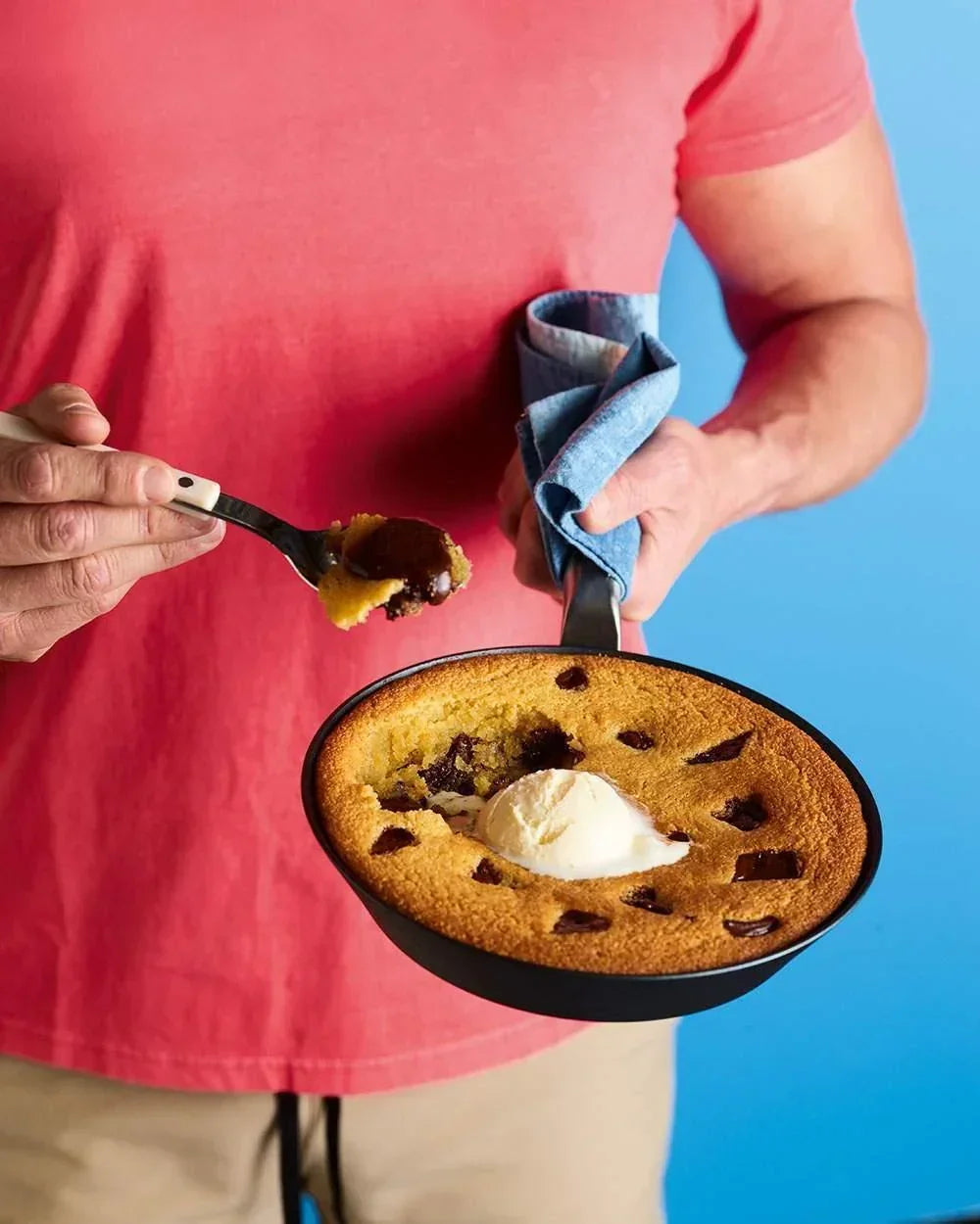 Person holding Mako black steel frying pan with baked dessert and ice cream, scooping with utensil