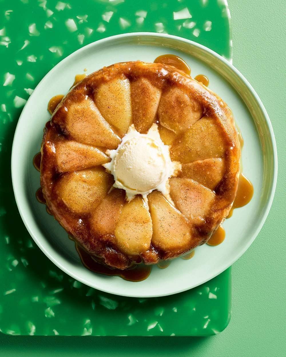 Upside down pear cake with caramel sauce and vanilla ice cream on a pale green plate
