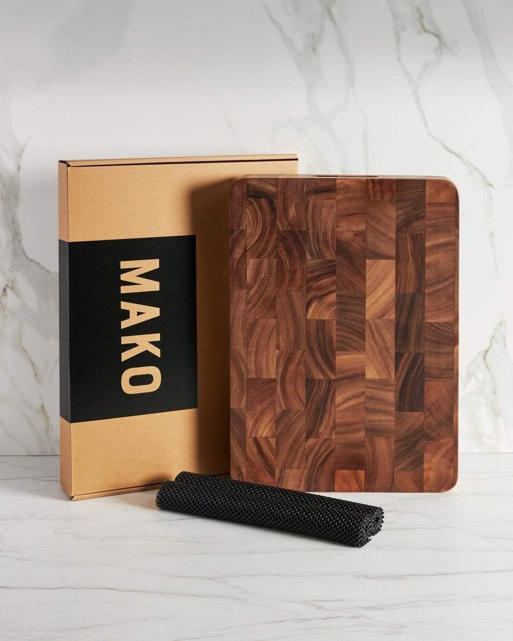 End grain wooden chopping board with non-slip mat and product box on marble countertop