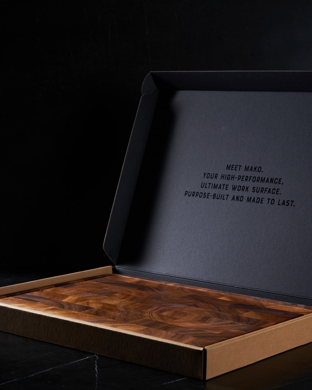 Premium wooden butcher's block with rich grain pattern in an open gift box on black background