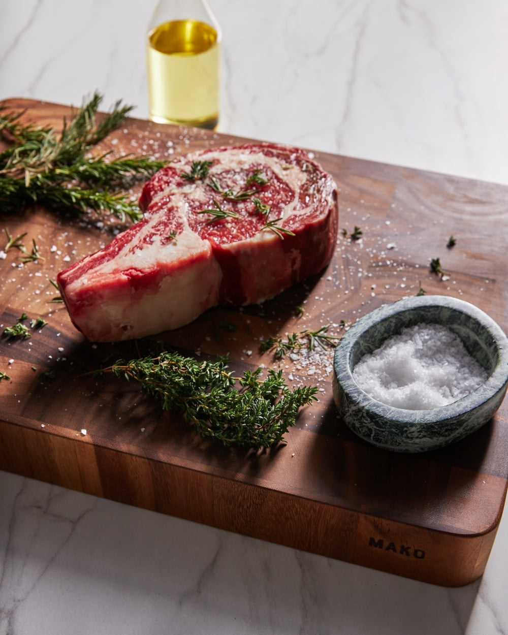 Raw steak with herbs and sea salt on wooden butchers block chopping board