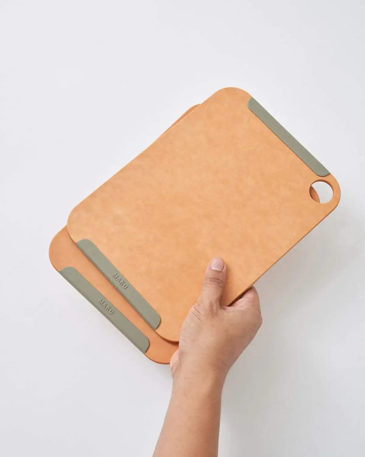 Hand holding set of two Mako non-slip wood fibre chopping boards with gray grip pads