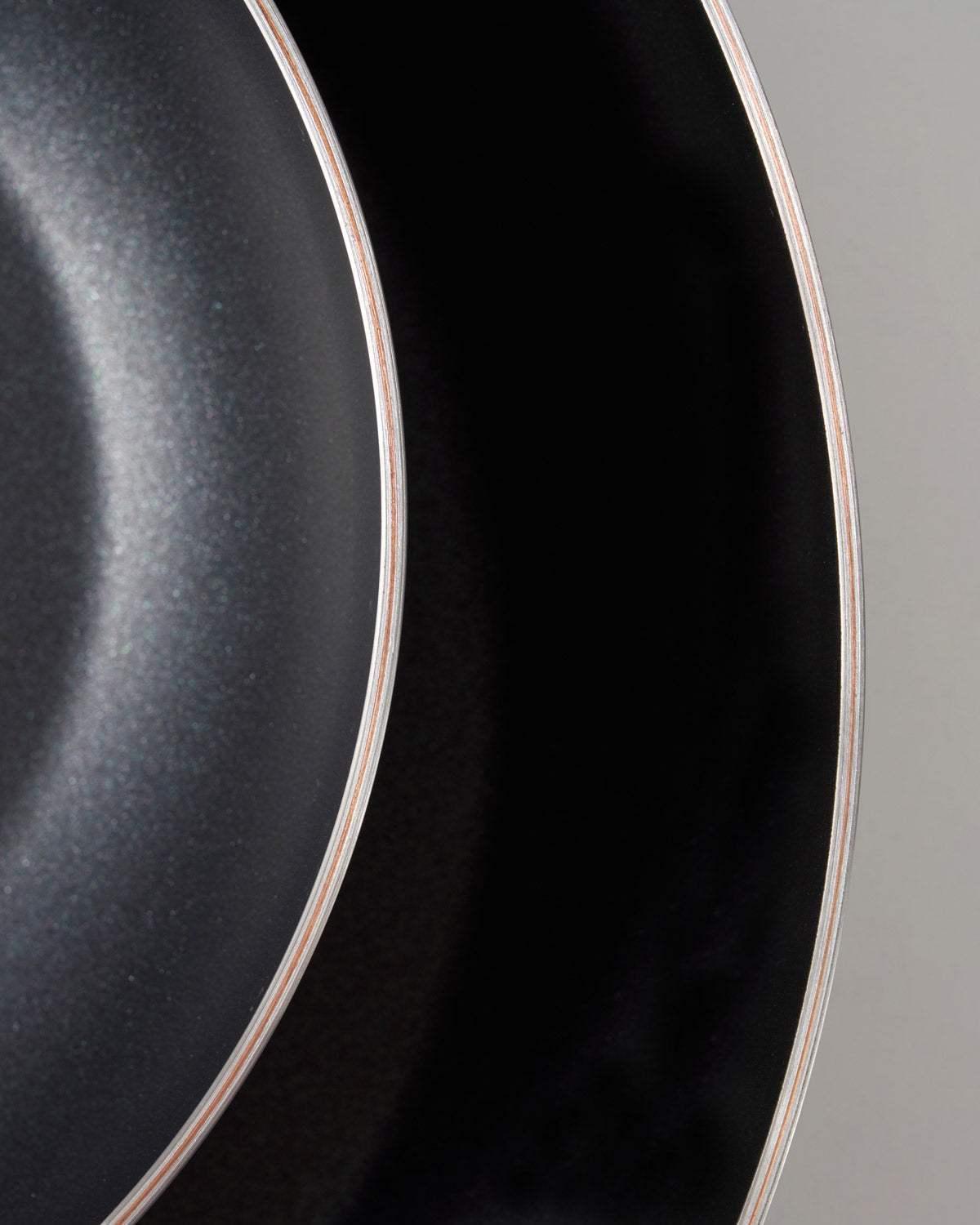 Close-up of Mako non-stick frying pans showing 5-ply layered design and smooth black cooking surface