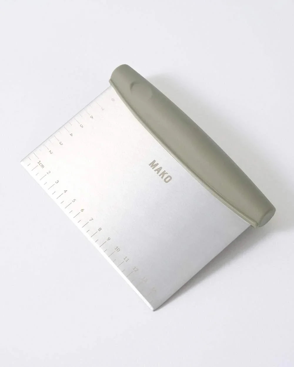 Mako stainless steel dough scraper with gray handle and centimeter ruler, kitchen tool by Marion Grasby