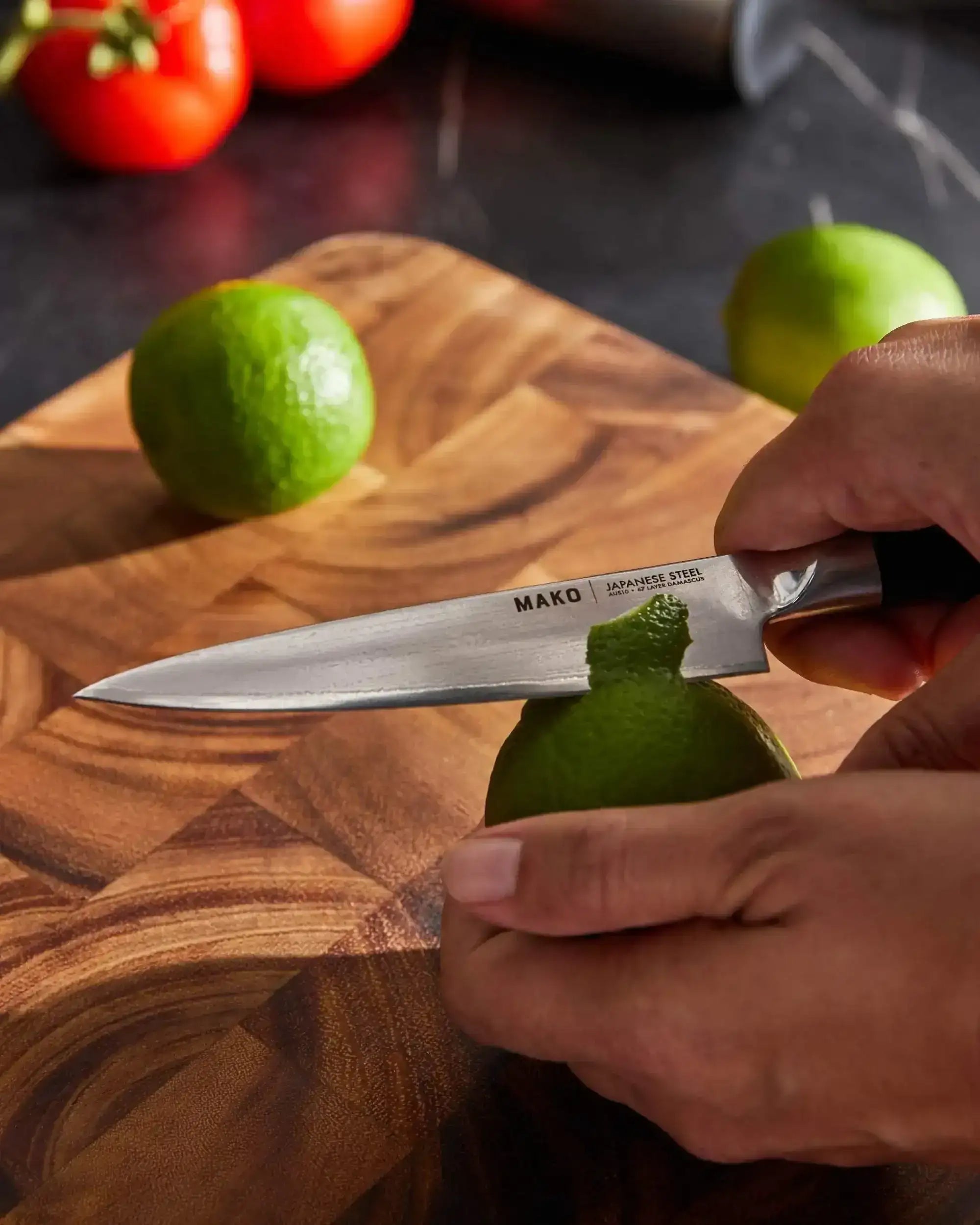 Hand peeling a lime with Mako Japanese steel kitchen knife on wooden cutting board