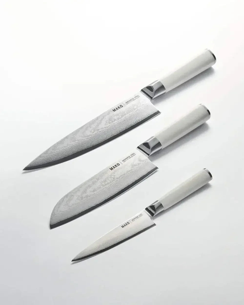 Three-piece Japanese steel kitchen knife set with cream handles on white background