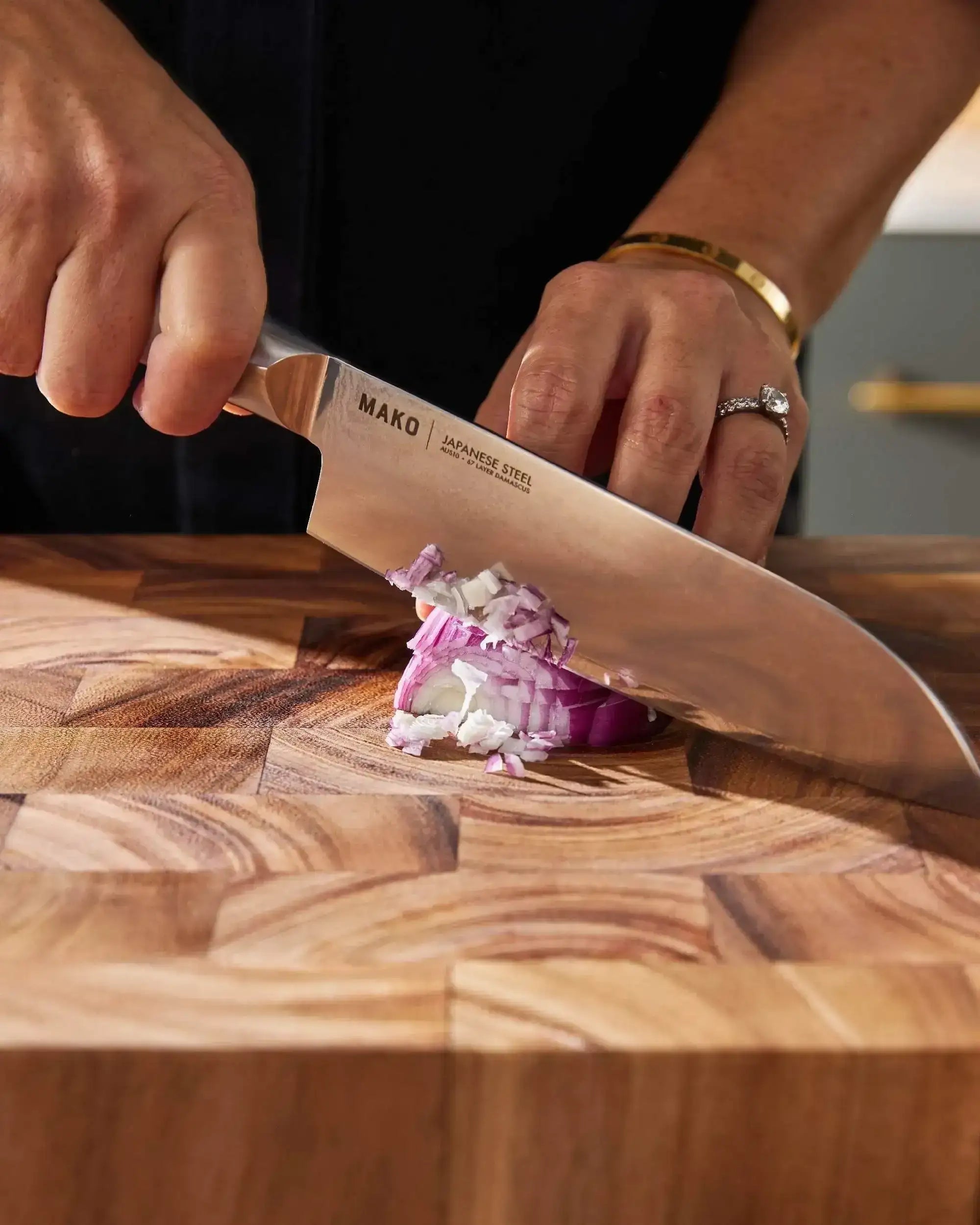 Japanese steel kitchen knife chopping red onion on wooden cutting board
