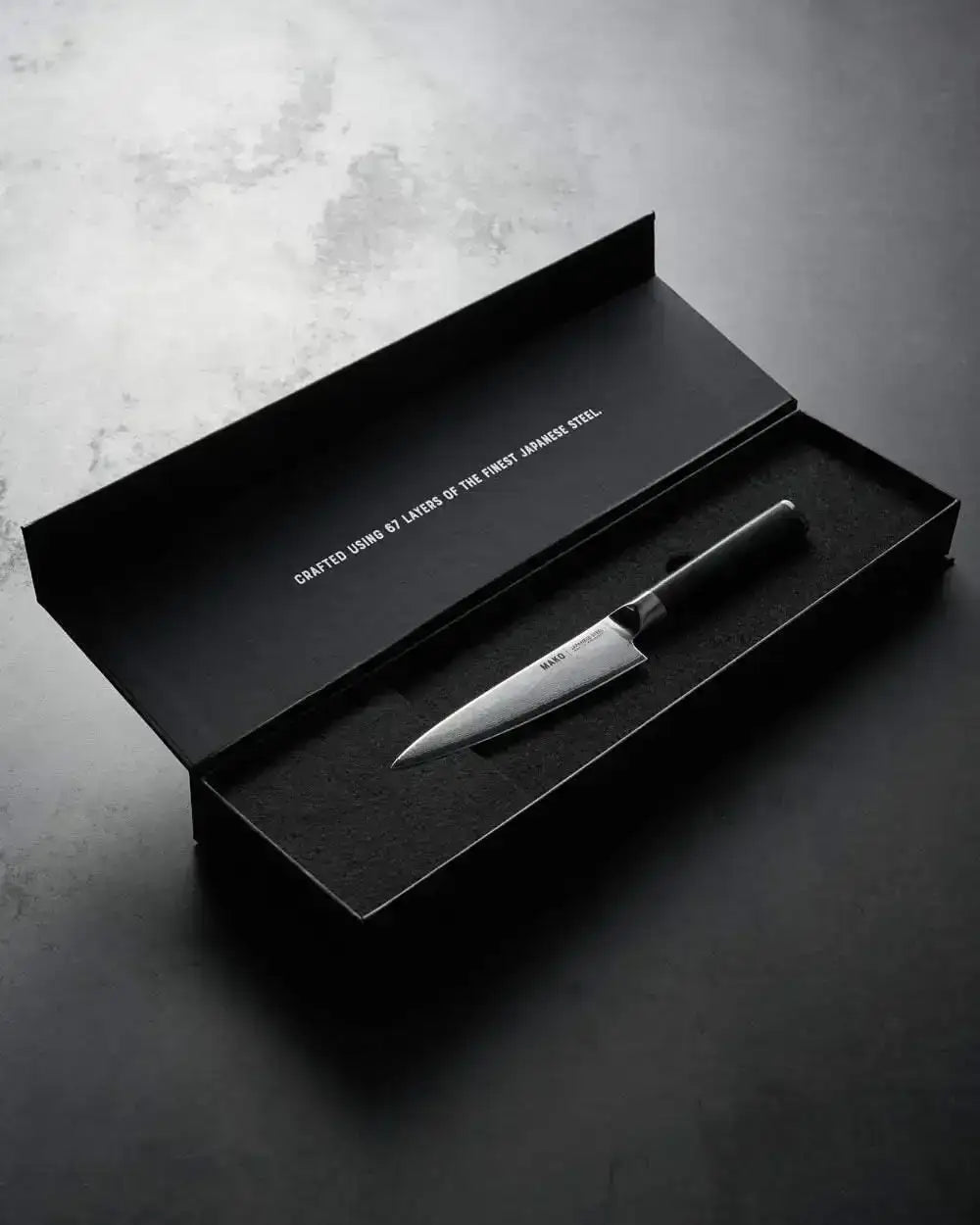 Mako Japanese steel kitchen knife with black handle in open black box, crafted from 67 Japanese steel layers