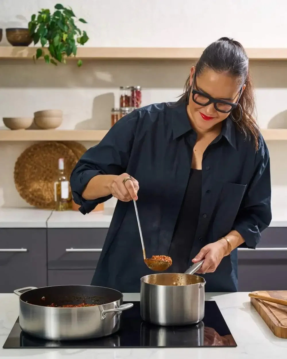 Woman cooking in modern kitchen using stainless steel saucepan on induction cooktop