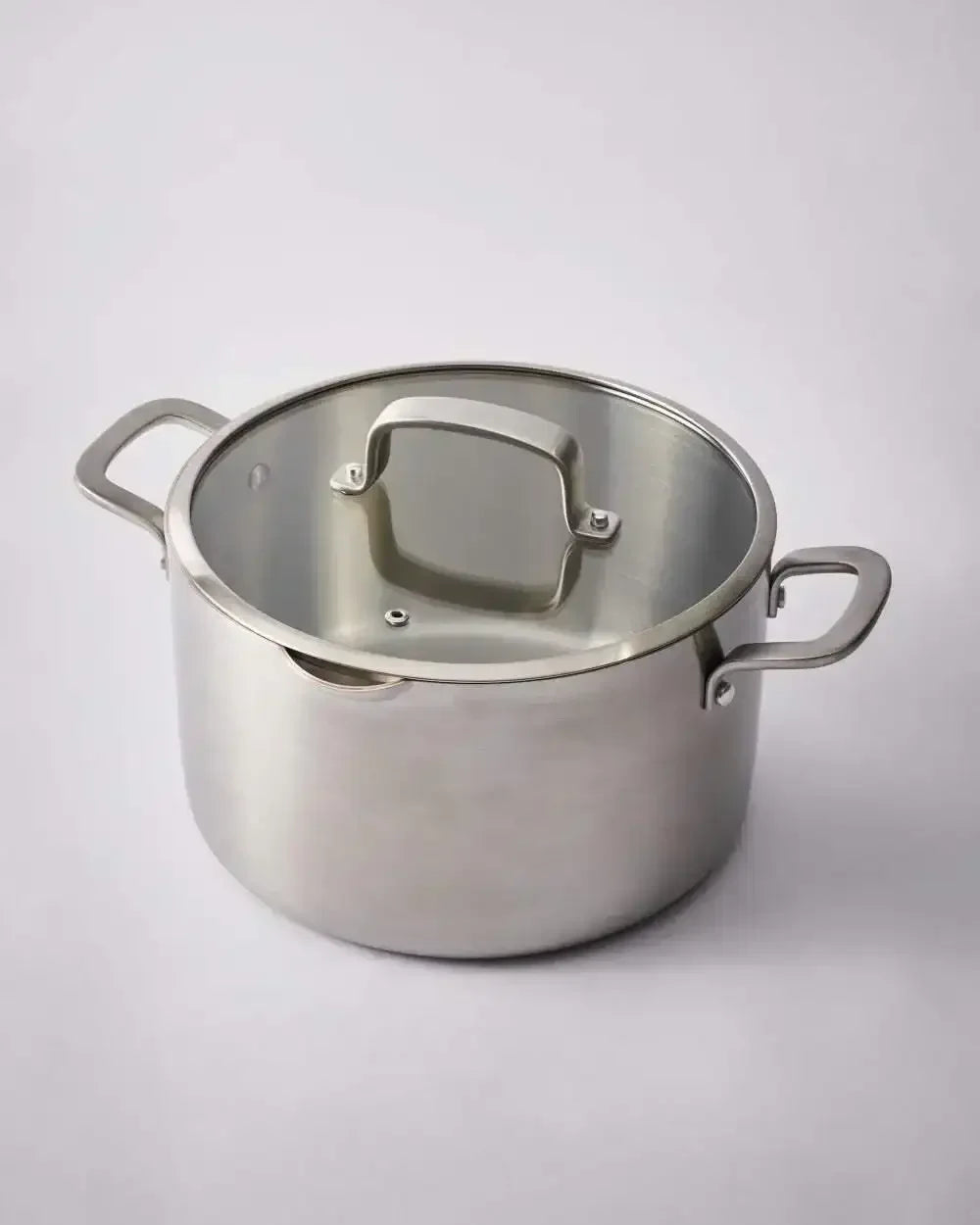 Stainless steel saucepan with lid and dual handles on a neutral background