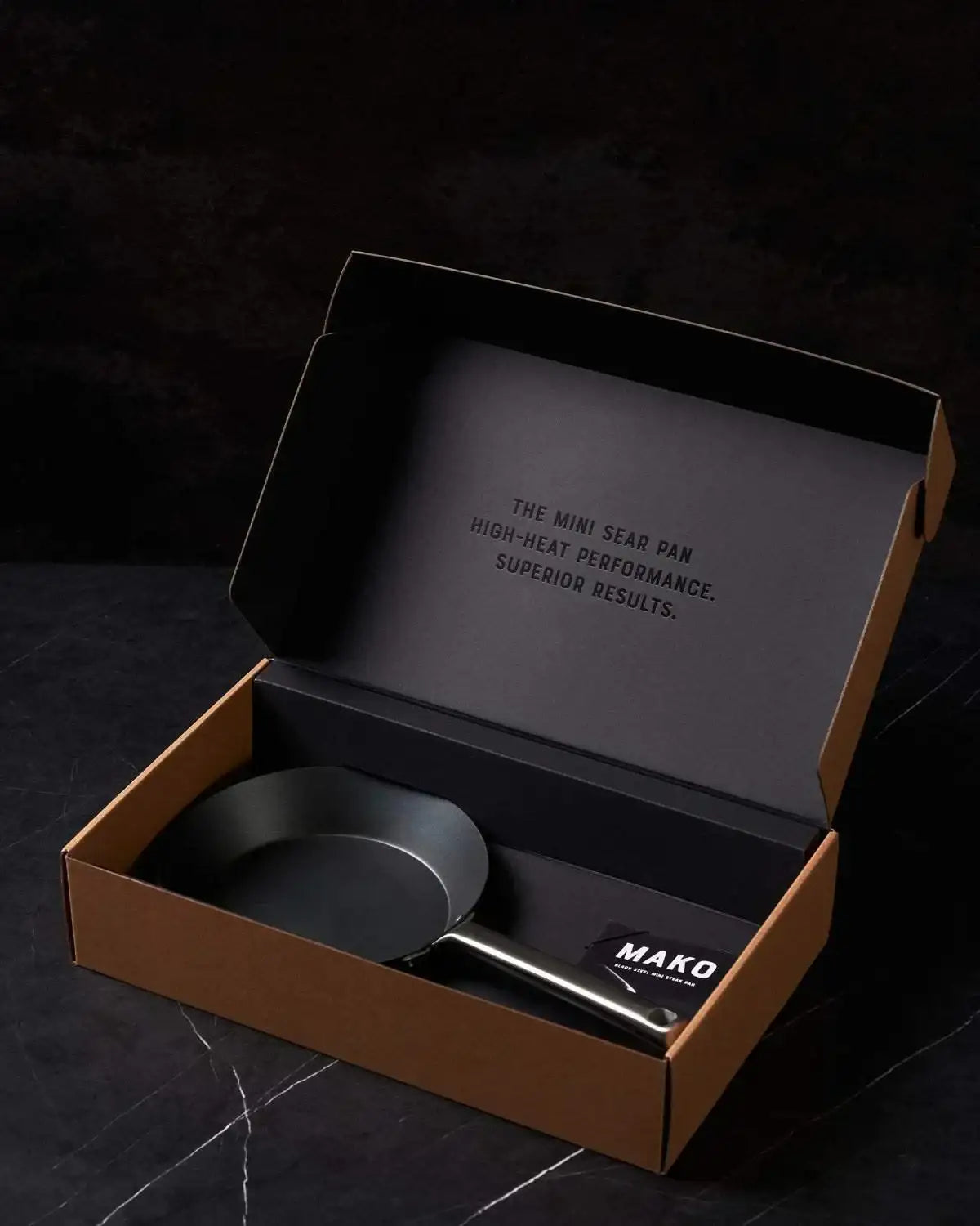 Black steel mini sear pan with metal handle in gift box on black marble surface