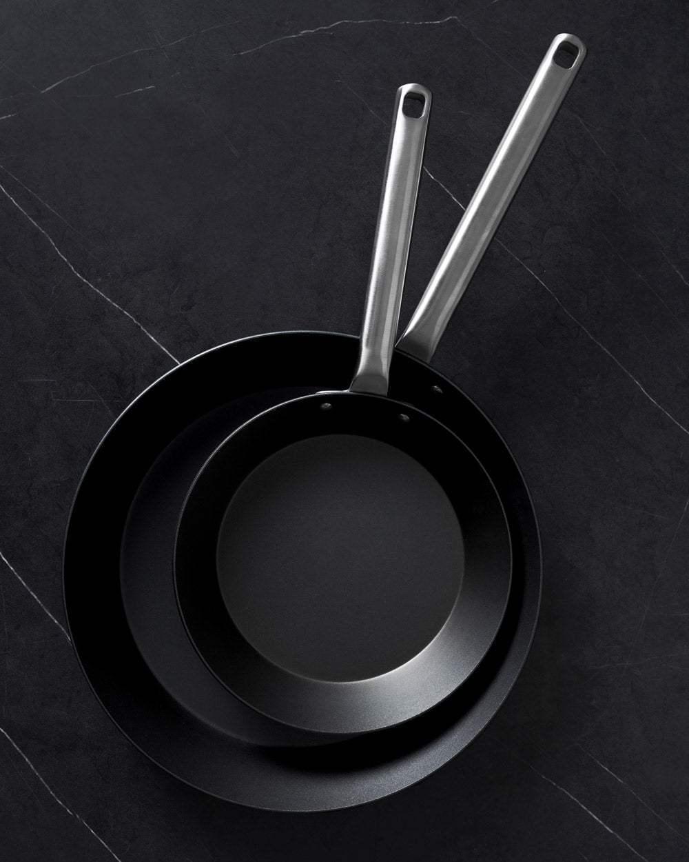 MAKO Black Steel Steak Pan Set CookDineHost - 2 pans on black marble table